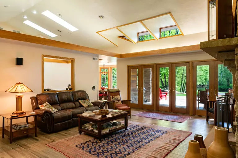 A room with seating lit with clerestory windows and three sets of French doors to an outdoor patio.