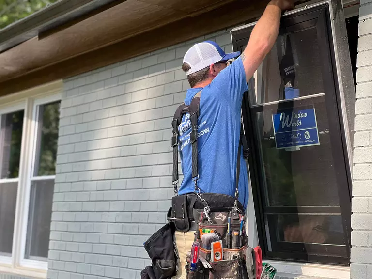 Window World worker setting a window with a black frame in a home.
