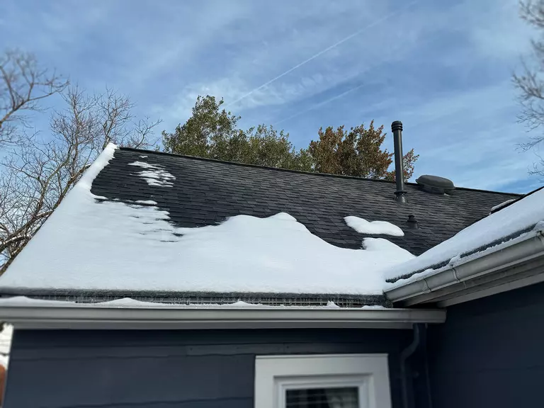 A thin layer of snow on a roof that has partially melted.
