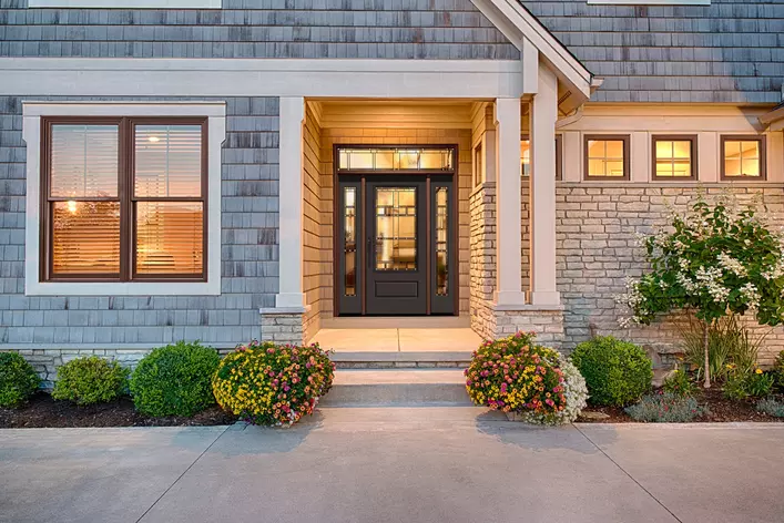 The front of a shake and stone home with varying sizes of insulated glass windows in the house.