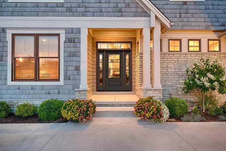 Exterior of a home at dusk, featuring an entry door with sidelites and a glass transom.