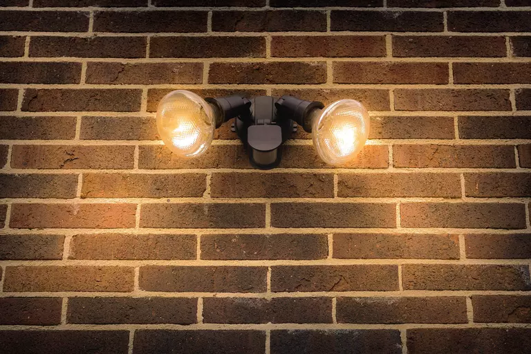 Exterior lights on a brick wall of a home at night.