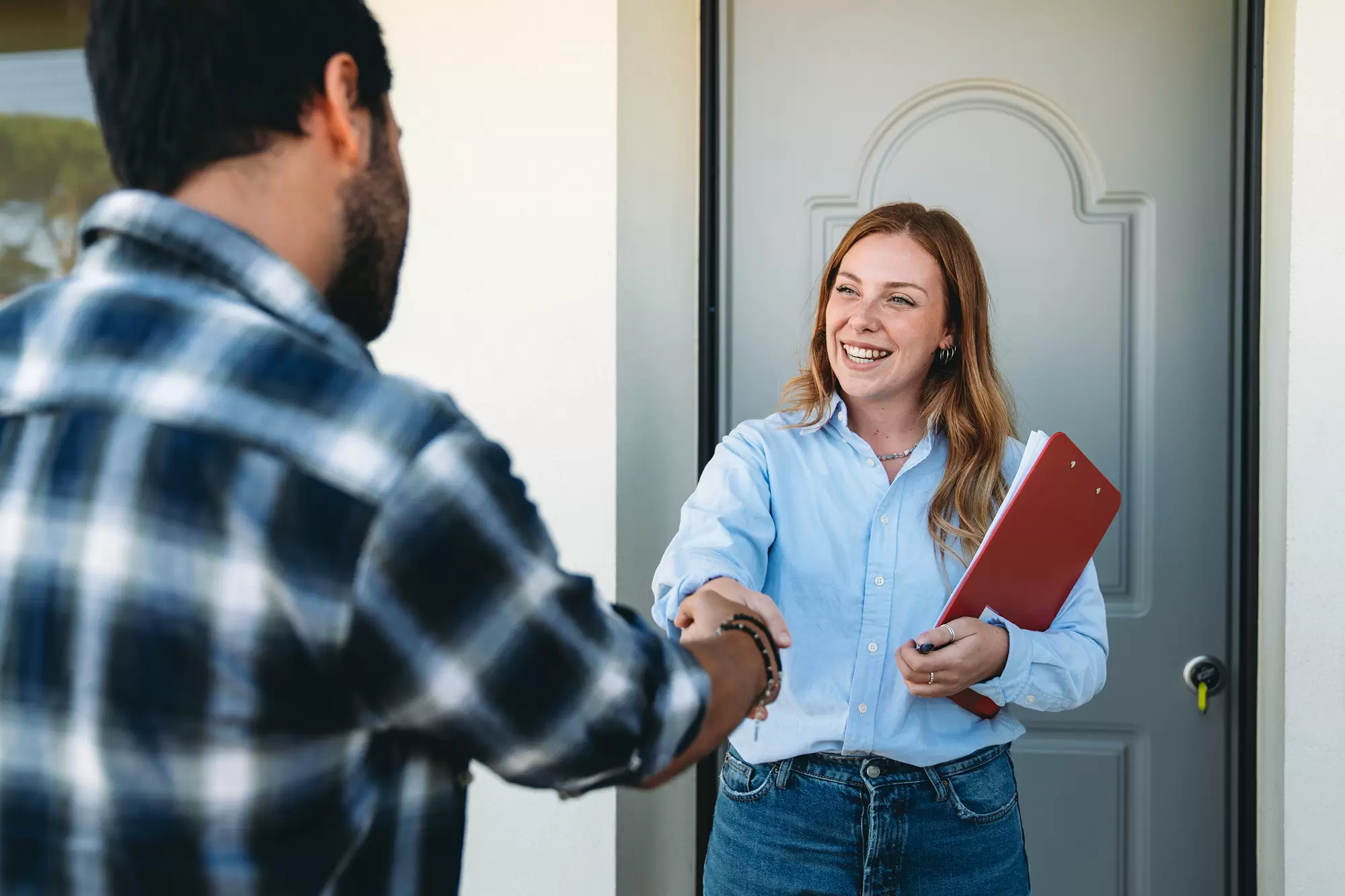 A representative greeting a homeowner at their front door.