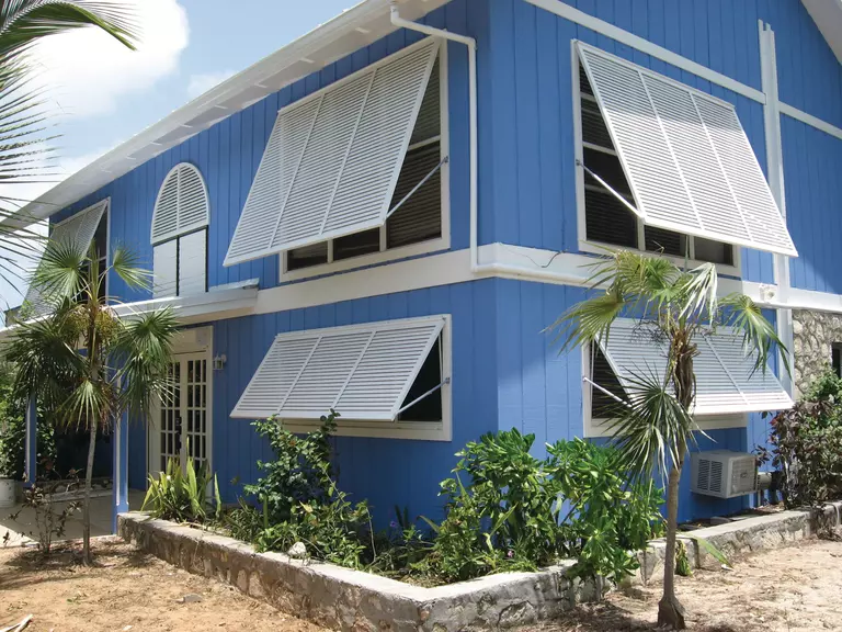 Hurricane shutters on a light blue home.