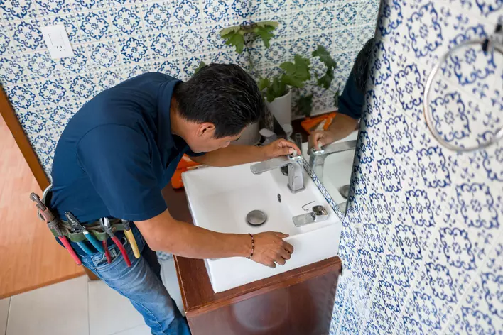 A handyman works on a faucet above a bathroom sink. Bathroom remodels are common
due to the smaller average size of bathrooms compared to kitchens and living rooms.