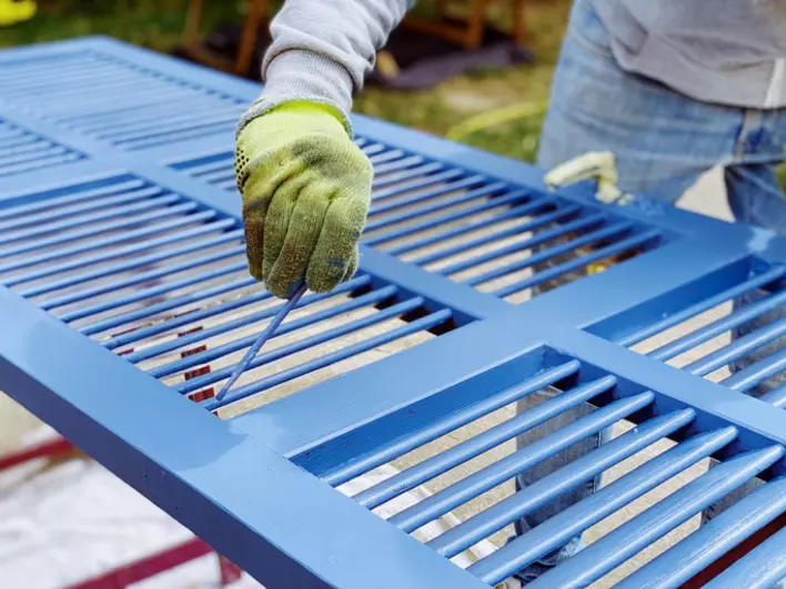 A contractor works with a blue hurricane panel before installing it on a home.