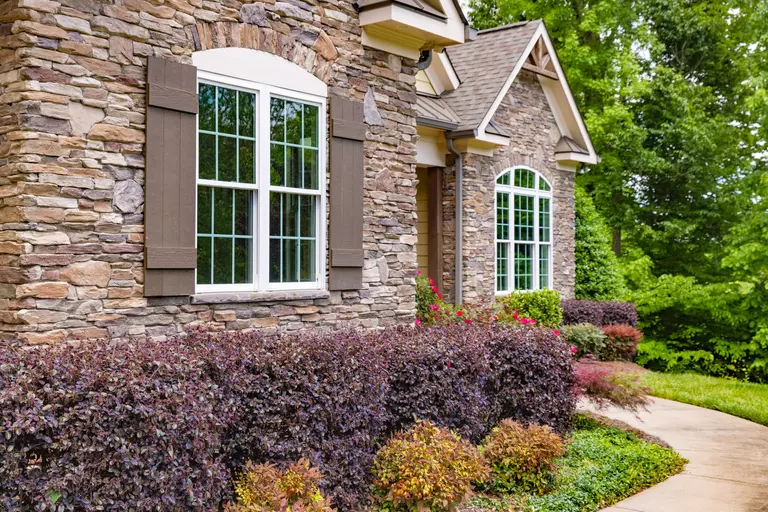 The front exterior of a home with stacked stone and arched windows.