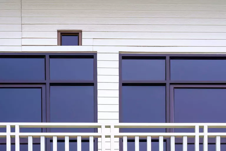 Glass doors on a white artificial wooden wall on the balcony of a two-story house.
