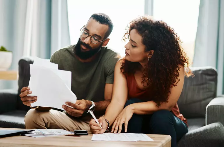 Two homeowners reviewing documents on a couch.