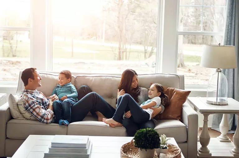 Family sitting on a couch, letting light in through their energy-efficient windows.