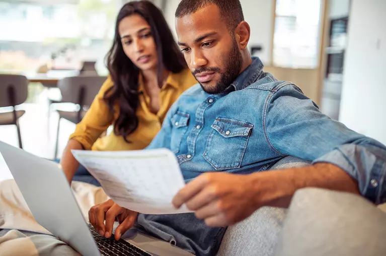 Man and woman going over paperwork and using a laptop.