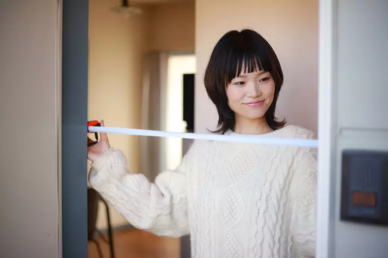 Woman measuring the width of a patio door entryway.