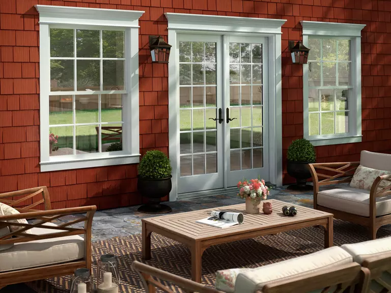 Exterior of a furnished patio featuring white hinged patio doors and double-hung windows.