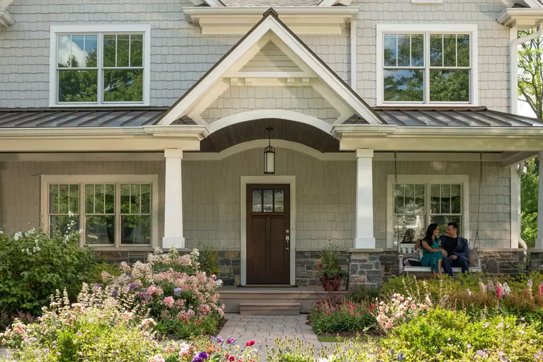 Young couple sitting on porch swing of home with a Therma Tru entry door.