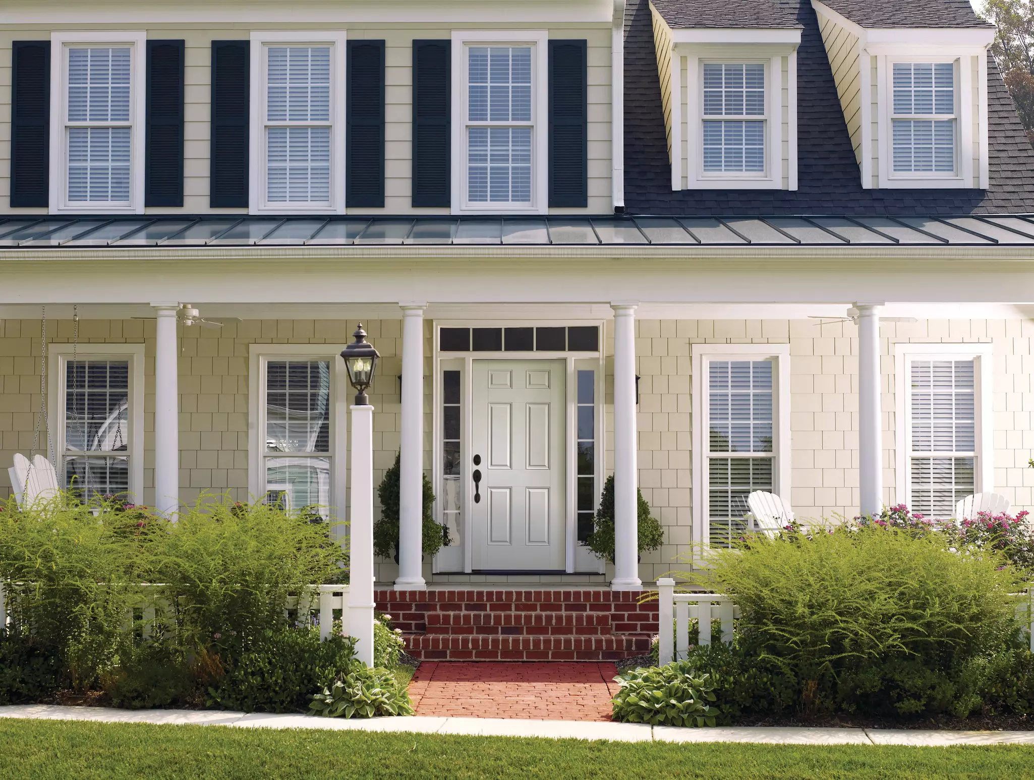Front of a home with multiple white windows with grids.