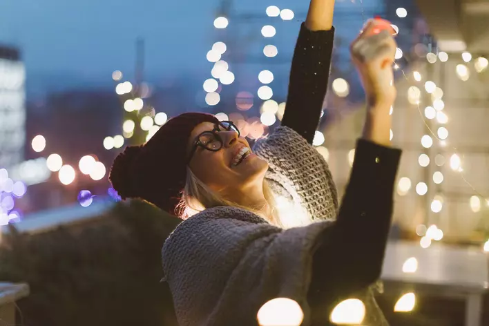 A woman dressed in warm winter clothing and a beanie hanging Christmas lights on the
exterior of her home.
