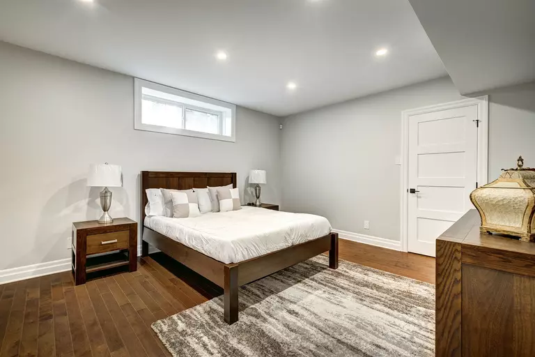 A bedroom in the basement of a home with an energy-efficient sliding window installed to bring in natural light. 