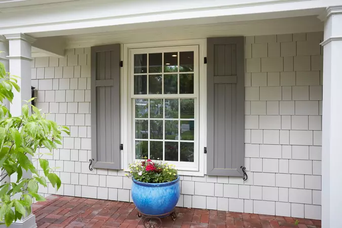 White exterior wood-clad double-hung windows with gray shutters
