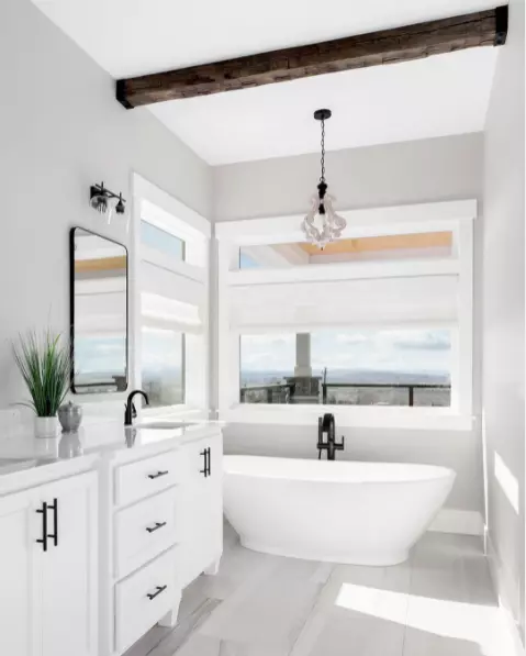 A charming bathroom with large windows, an exposed beam, and a comfy tub