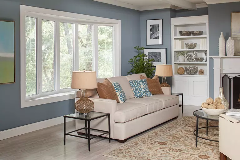 The living room of a home with blue walls and a large bay window.