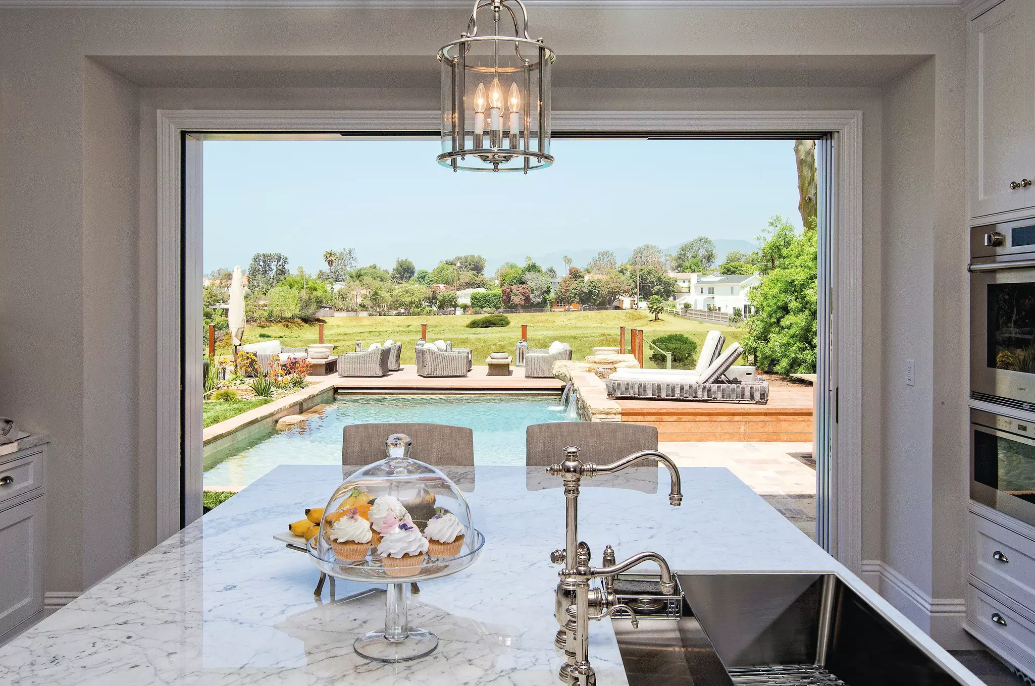 Windsor multi-slide patio door open showing the outside patio with pool and the interior kitchen.