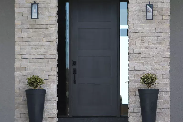 A steel entry door with a modern design on a stone entryway.