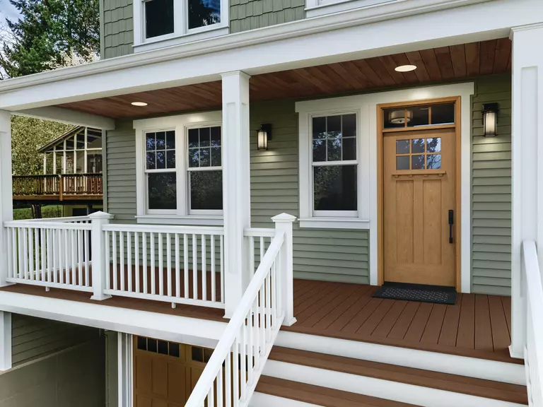 The elevated porch of a multi-level home with a combination of double-hung windows near the front door.