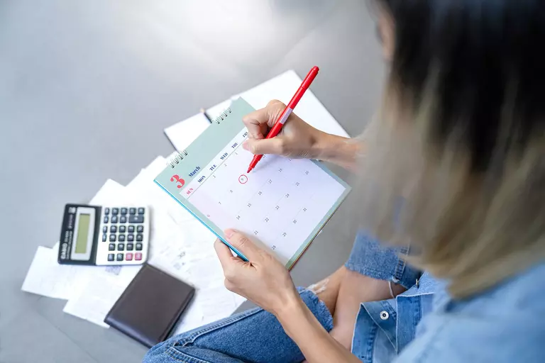 Woman circling a date on a calendar.