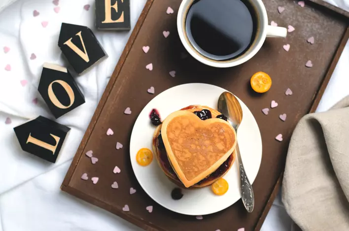 Breakfast tray with heart-shaped pancake and wooden block letters that spell out “Love”