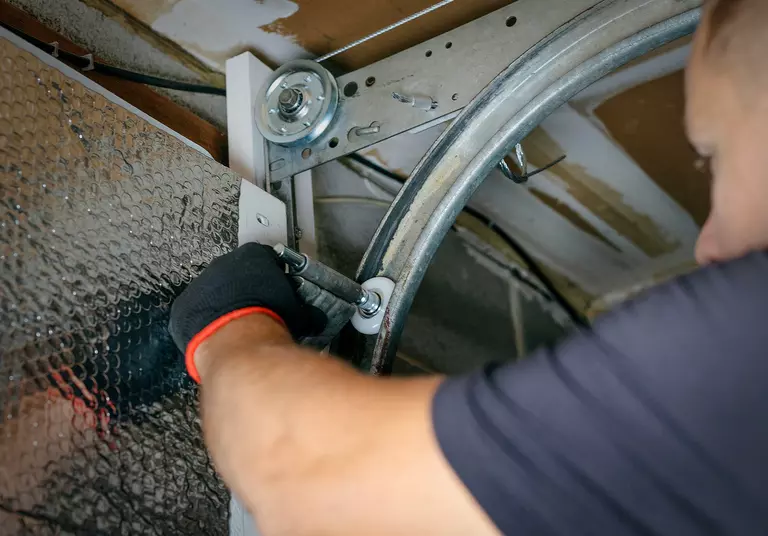 Worker adjusting the mechanisms of a garage door.