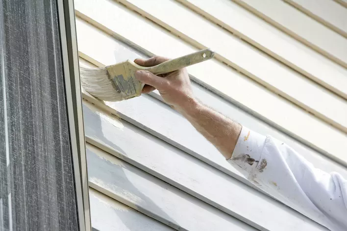 A person repaints the vinyl siding of their home’s exterior. Paint ideas for home
remodeling are common.