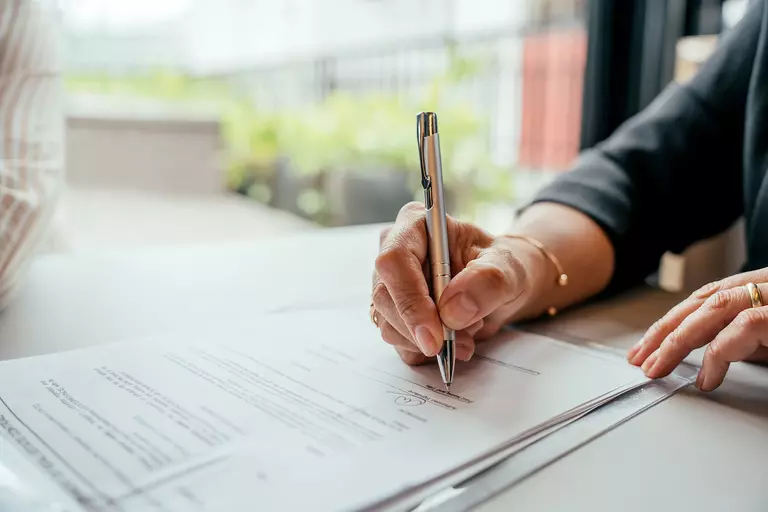 Woman signing a document with a pen.