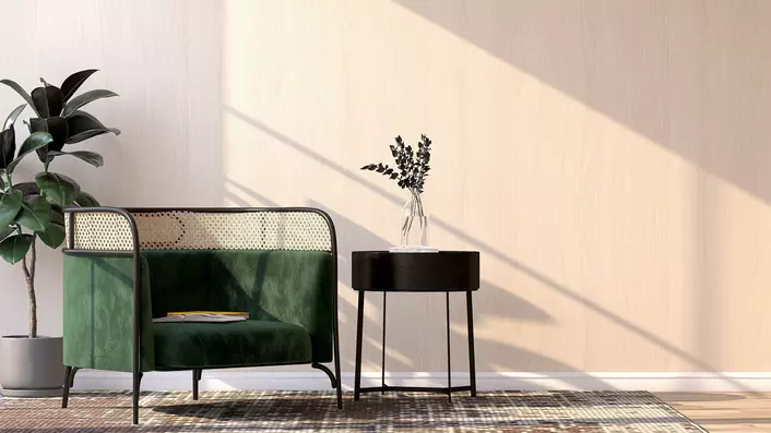 A green velvet chair, side table, standing plant, and rug all in a neutral-toned room illuminated by natural light coming in through energy-efficient windows. 