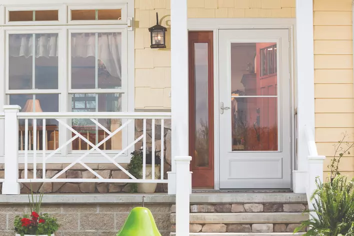 A full view storm door to the entryway of a peach-colored home.