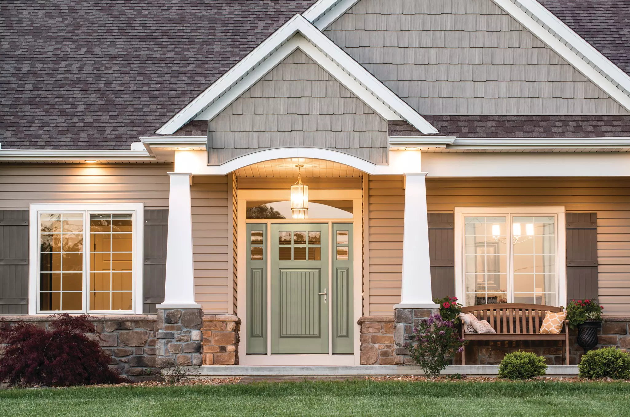 Front face of a home featuring a light-green entry door with sidelites and window grids.