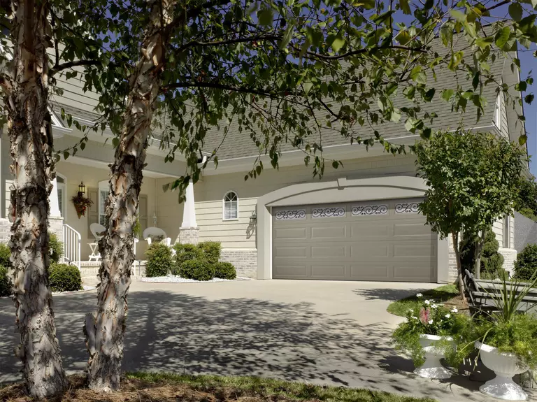 Home with a gray raised panel garage door with decorative windows.