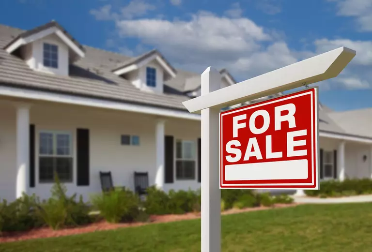 For Sale sign in front of the porch of a two-story home.