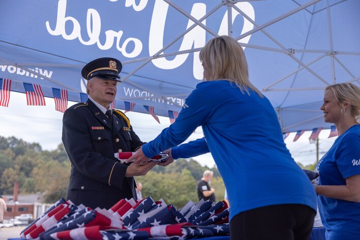 Woman handing out American flags to veterans at Window World booth 