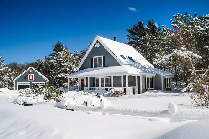 View of a home and garage covered in snow