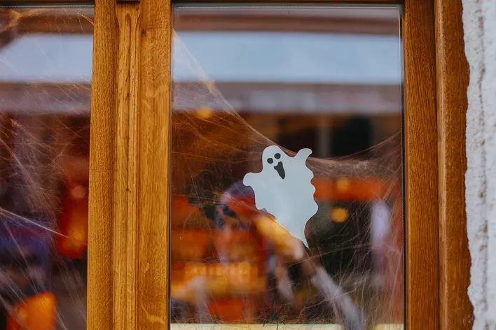Paper cut ghost and cobweb decorations on a window