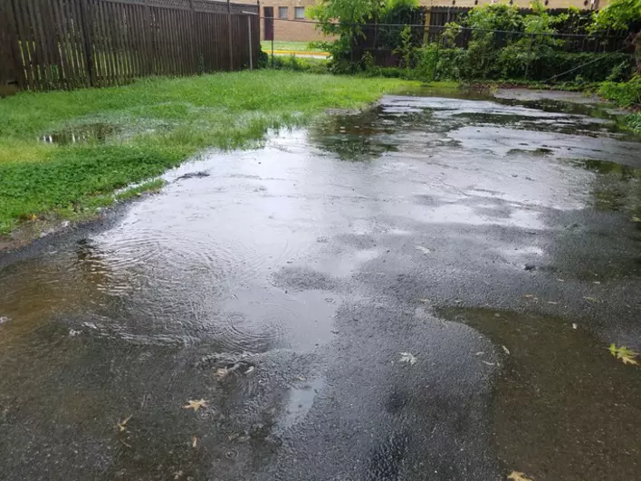 Large water puddle from rain in driveway and grass