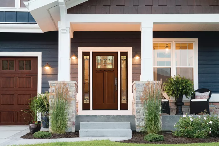 Front porch of a home featuring a brown front door with full glass sidelites.