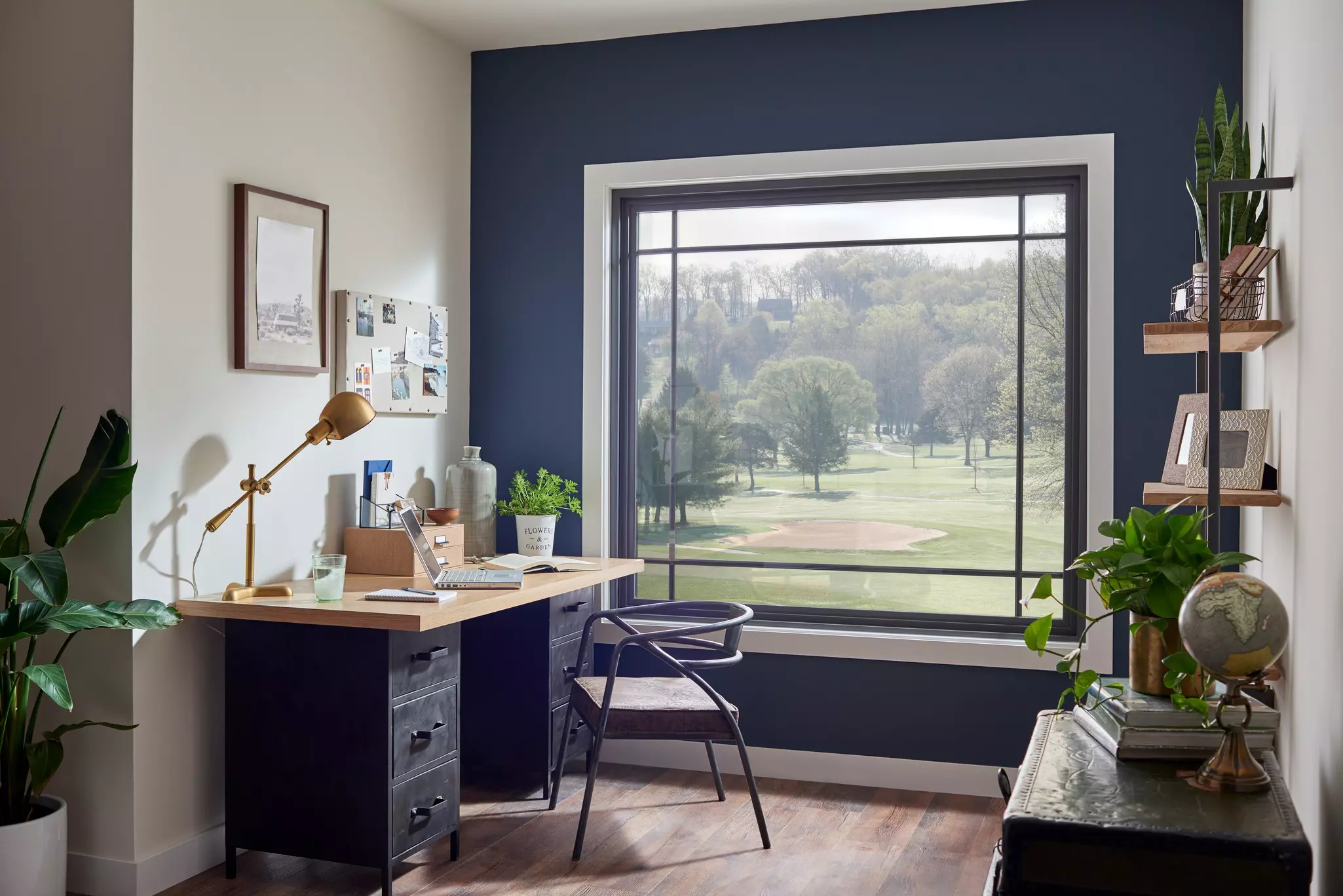 Home office with a large picture window framing a green tree view.