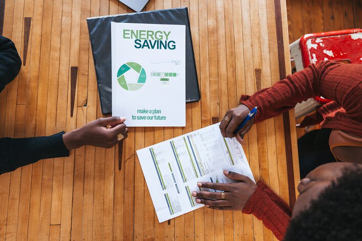 Two people going over paperwork about energy saving thanks to the benefits of natural light in home.
