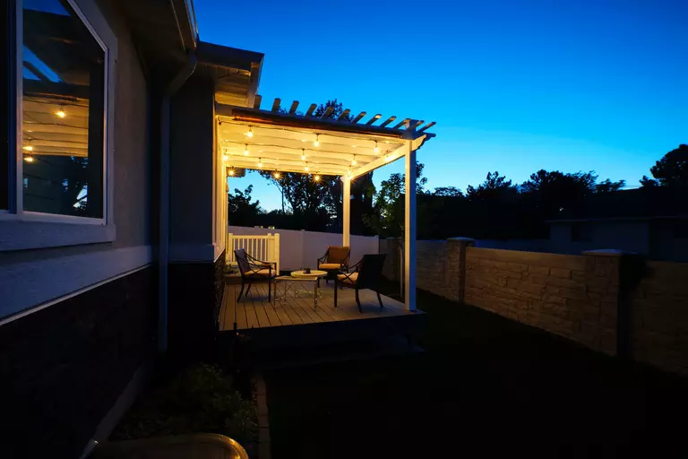 A group of lightbulbs casts warm, inviting light over a back porch outdoor living space.