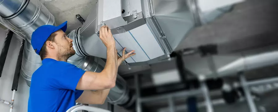 A male professional performing a home energy audit on a heating and cooling system