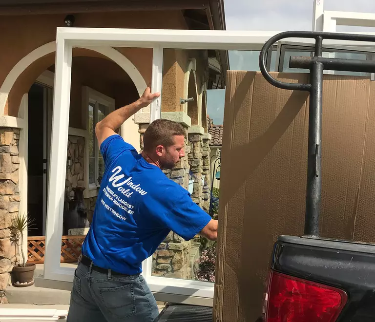 Window World installation expert unloading a large window from a truck.
