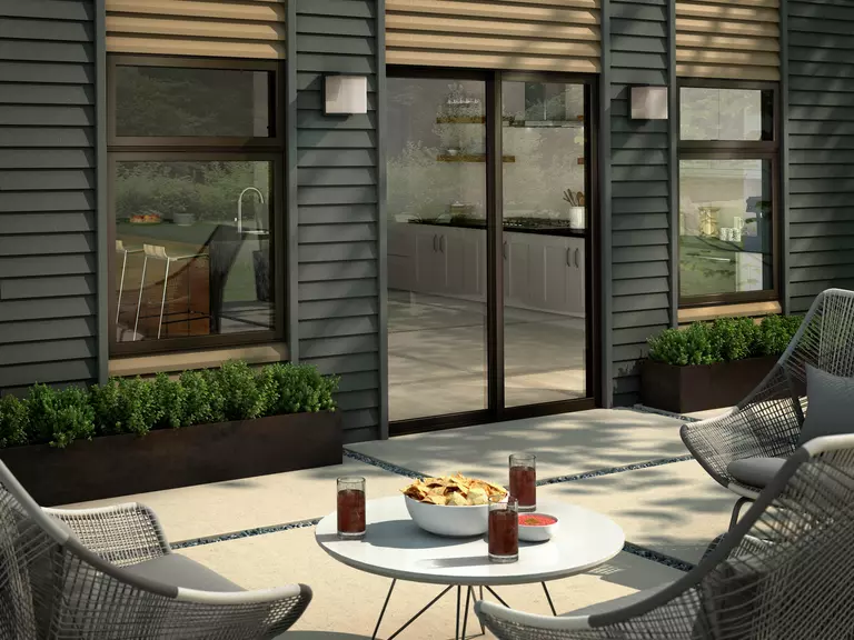 Snacks and drinks sit on a circular table within view of the back patio door of a modern home. The area looks welcoming and relaxing to spend time in.