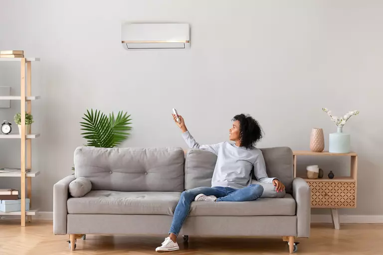 Person turning on their home cooling system from their couch.