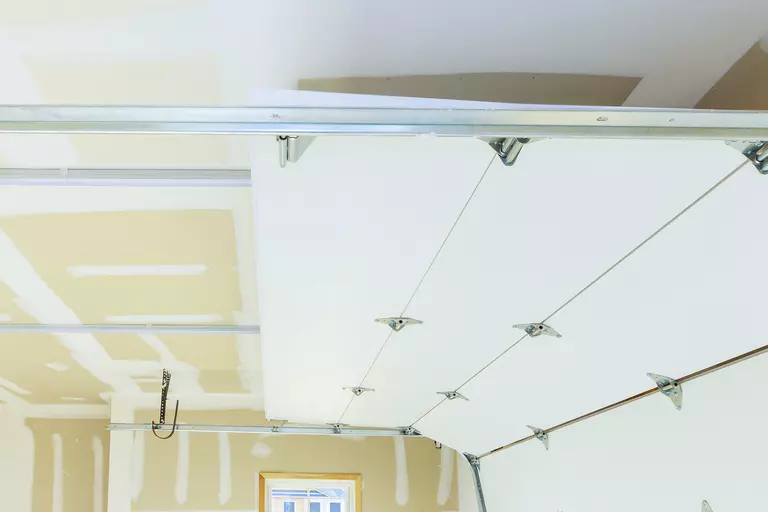 The top of a garage door, partially open from the inside of an unfinished garage.